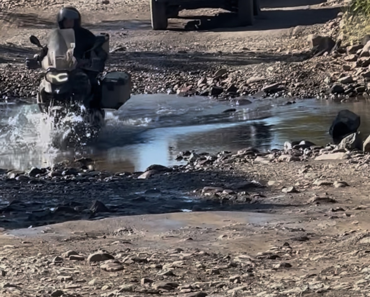 A motorcyclist riding through a water crossing in the outback